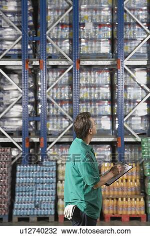 Stock Image - Warehouse Worker Checking Inventory side view. Fotosearch