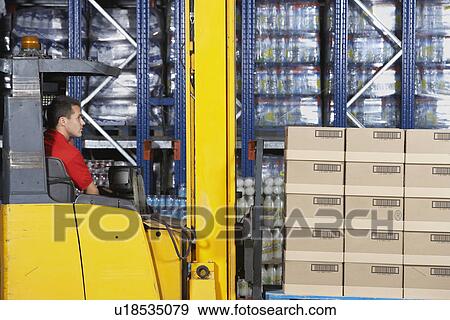 Stock Photo - Warehouse Worker Operating Forklift side view. Fotosearch