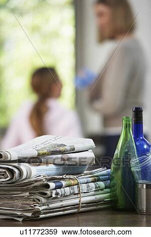 Stock Photo - Waste paper and bottles on table woman and girl in background. Fotosearch