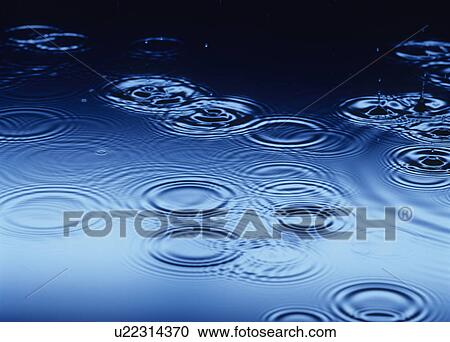 Stock Image - Water drops splashing making Ripples on Water. Fotosearch