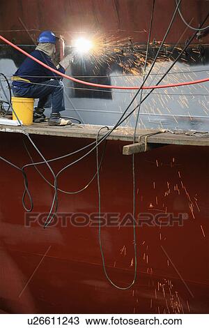 Welder working on side of ship in dry dock View Large Photo Image Stock Image - Welder working on side of ship in dry dock. Fotosearch