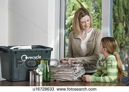 Stock Image - Woman and girl preparing waste paper for recycling. Fotosearch