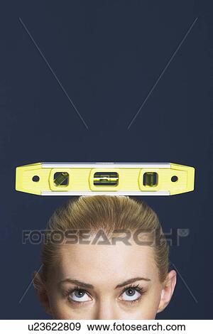 Woman balancing spirit level on her head against dark background high section View Large Photo Image Stock Photo - Woman balancing spirit level on her head against dark background high section. Fotosearch