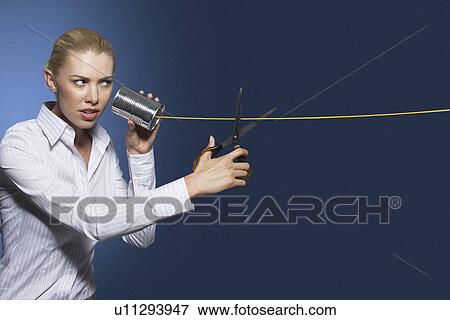 Stock Photo - Woman cutting line on tin can string phone against dark background. Fotosearch