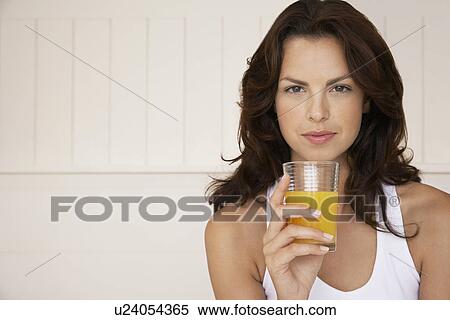 Stock Photography - Woman drinking glass of orange juice half length. Fotosearch