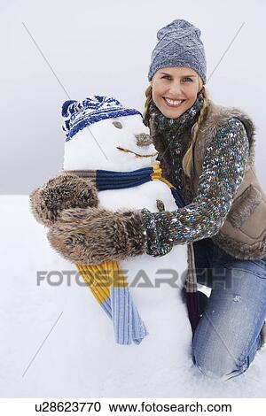 Woman embracing snowman kneeling on snow-covered hill portrait View Large Photo Image Stock Image - Woman embracing snowman kneeling on snow-covered hill portrait. Fotosearch