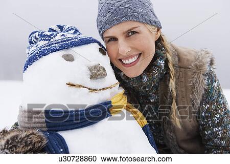 Stock Image - Woman embracing snowman portrait close up. Fotosearch