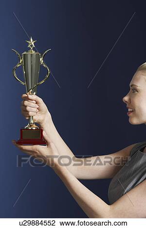 Woman holding and admiring trophy against dark background profile View Large Photo Image Stock Image - Woman holding and admiring trophy against dark background profile. Fotosearch