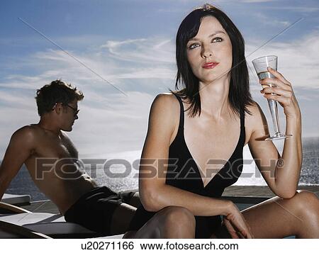 Woman holding champagne glass man relaxing near sea View Large Photo Image Stock Photograph - Woman holding champagne glass man relaxing near sea. Fotosearch