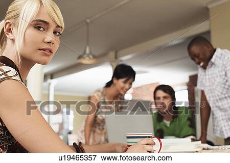 Woman holding cup with three people around laptop in background. View Large Photo Image Stock Photo - Woman holding cup with three people around laptop in background.. Fotosearch