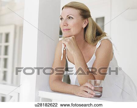 Woman holding glass of water leaning on verandah balustrade portrait View Large Photo Image Stock Image - Woman holding glass of water leaning on verandah balustrade portrait. Fotosearch