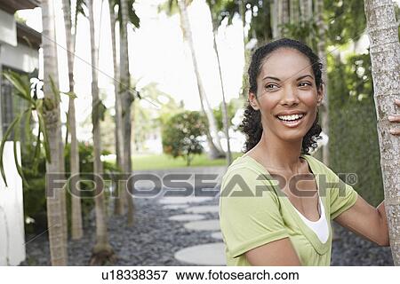 Woman holding on to palm tree smiling View Large Photo Image Stock Photo - Woman holding on to palm tree smiling. Fotosearch