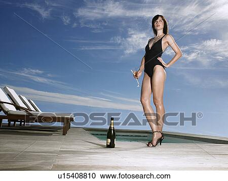 Woman in bathing suit holding champagne at poolside View Large Photo Image Stock Image - Woman in bathing suit holding champagne at poolside. Fotosearch