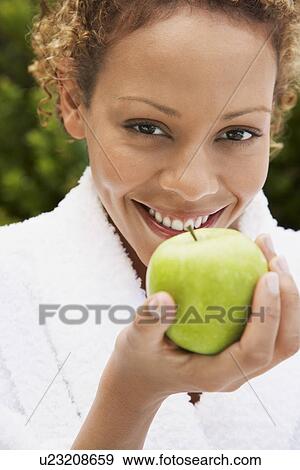 Stock Photo - Woman in bathrobe holding apple head and shoulders. Fotosearch