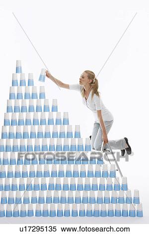 Woman kneeling on ladder to stack plastic cups into pyramid against white background View Large Photo Image Stock Photography - Woman kneeling on ladder to stack plastic cups into pyramid against white background. Fotosearch