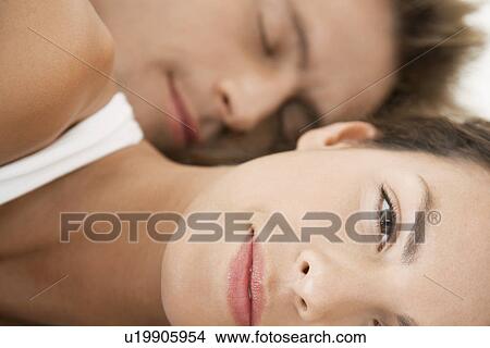 Picture - Woman lying down close up man in background. Fotosearch