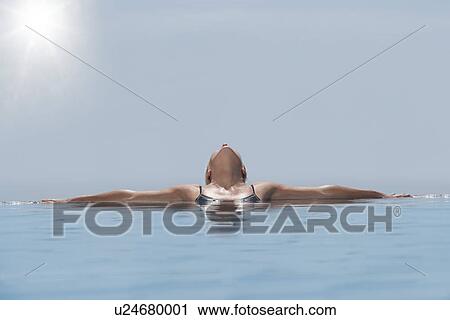 Woman lying head back sunbathing in pool View Large Photo Image Stock Image - Woman lying head back sunbathing in pool. Fotosearch