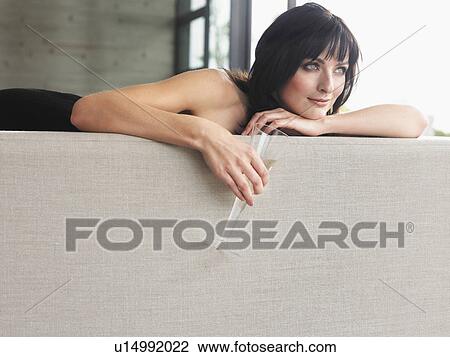 Woman lying on couch with champagne in living room View Large Photo Image Stock Image - Woman lying on couch with champagne in living room. Fotosearch
