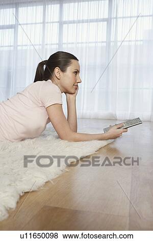 Woman lying on floor watching television View Large Photo Image Stock Photo - Woman lying on floor watching television. Fotosearch
