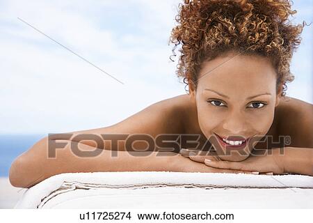 Woman lying on massage table head and shoulders eye contact View Large Photo Image Picture - Woman lying on massage table head and shoulders eye contact. Fotosearch