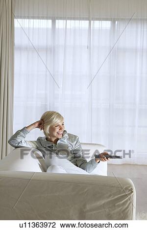 Woman lying on sofa watching television View Large Photo Image Stock Image - Woman lying on sofa watching television. Fotosearch