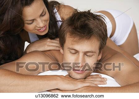 Stock Image - Woman massaging man lying in bed. Fotosearch