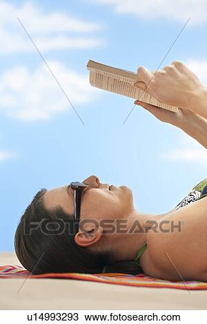 Woman reading book lying on beach side view View Large Photo Image Stock Image - Woman reading book lying on beach side view. Fotosearch