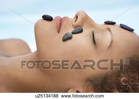 Stock Photo - Woman receiving hot stone therapy head and shoulders close-up. Fotosearch
