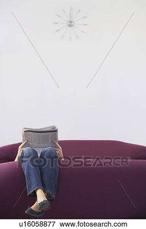 Stock Photo - Woman Relaxing upside down on Sofa reading newspaper low section. Fotosearch