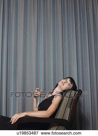 Woman sitting in chair holding champagne indoors View Large Photo Image Stock Photo - Woman sitting in chair holding champagne indoors. Fotosearch