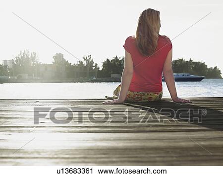 Woman sitting on edge of jetty back view View Large Photo Image Stock Image - Woman sitting on edge of jetty back view. Fotosearch