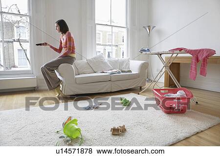 Woman sitting on edge of sofa watching television View Large Photo Image Stock Photo - Woman sitting on edge of sofa watching television. Fotosearch