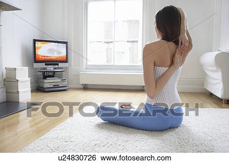 Woman sitting on floor stretching arms behind back and watching television back view View Large Photo Image Stock Photograph - Woman sitting on floor stretching arms behind back and watching television back view. Fotosearch