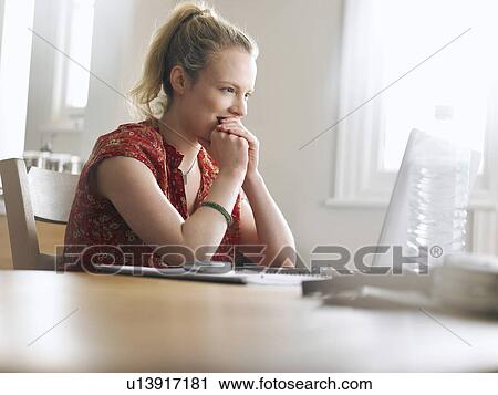 Woman using laptop sitting at dining table low angle view View Large Photo Image Stock Image - Woman using laptop sitting at dining table low angle view. Fotosearch