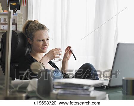 Woman using laptop sitting at office View Large Photo Image Stock Image - Woman using laptop sitting at office. Fotosearch