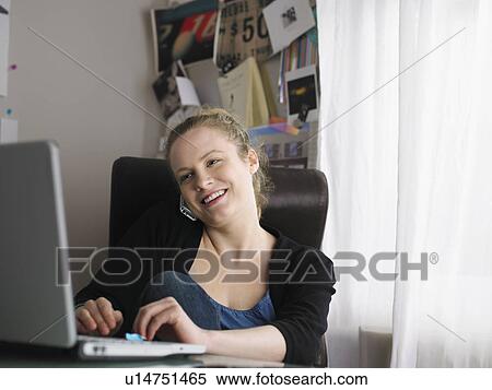 Woman using laptop sitting at office View Large Photo Image Stock Photography - Woman using laptop sitting at office. Fotosearch