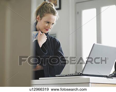 Woman using laptop standing in kitchen low angle view View Large Photo Image Stock Photo - Woman using laptop standing in kitchen low angle view. Fotosearch