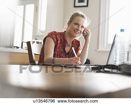 Woman using mobile phone sitting at dining table low angle view View Large Photo Image Stock Photograph - Woman using mobile phone sitting at dining table low angle view. Fotosearch