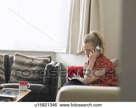 Woman using mobile phone sitting in living room elevated view View Large Photo Image Stock Photograph - Woman using mobile phone sitting in living room elevated view. Fotosearch