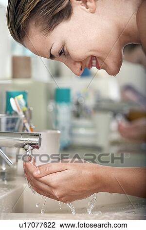 Stock Image - Woman washing face in bathroom close-up. Fotosearch