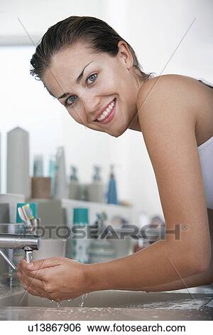 Woman washing face in bathroom View Large Photo Image Stock Photograph - Woman washing face in bathroom. Fotosearch