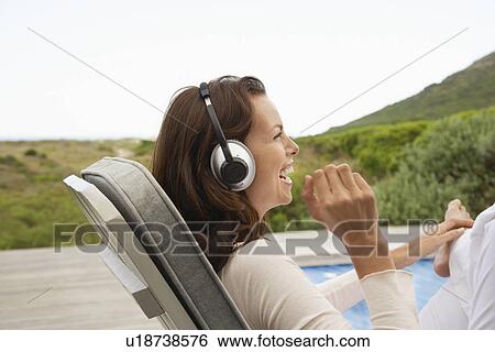 Woman wearing headphones laughing profile View Large Photo Image Stock Photograph - Woman wearing headphones laughing profile. Fotosearch