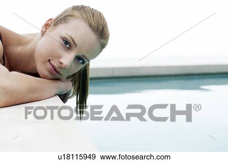 Stock Photo - Women lying at edge of swimming pool portrait. Fotosearch
