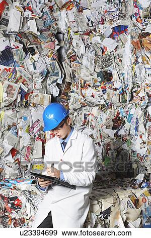 Worker holding clipboard sitting on stacks of recycled paper portrait View Large Photo Image Stock Photo - Worker holding clipboard sitting on stacks of recycled paper portrait. Fotosearch