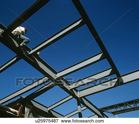 Stock Photo - Worker sitting on iron construction low angle view. Fotosearch