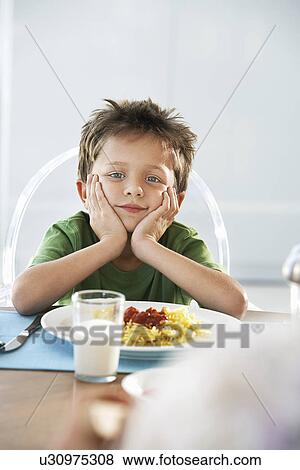 Young boy with head in hands at dinner table View Large Photo Image Stock Photo - Young boy with head in hands at dinner table. Fotosearch