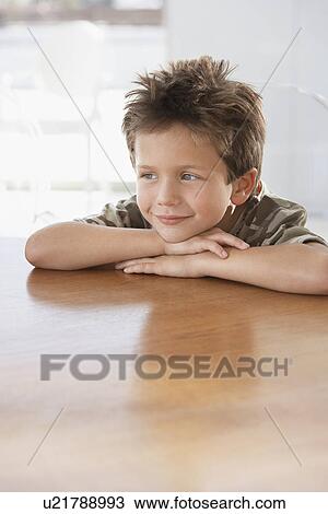 Stock Image - Young Boy with His Head on hands resting on the Table. Fotosearch