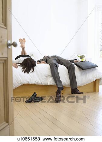 Young business couple lying on bed in bedroom View Large Photo Image Stock Photo - Young business couple lying on bed in bedroom. Fotosearch