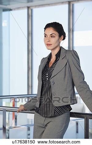 Stock Image - Young businesswoman standing in office corridor. Fotosearch