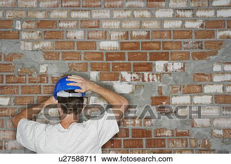 Stock Image - Young construction worker by brick wall back view. Fotosearch